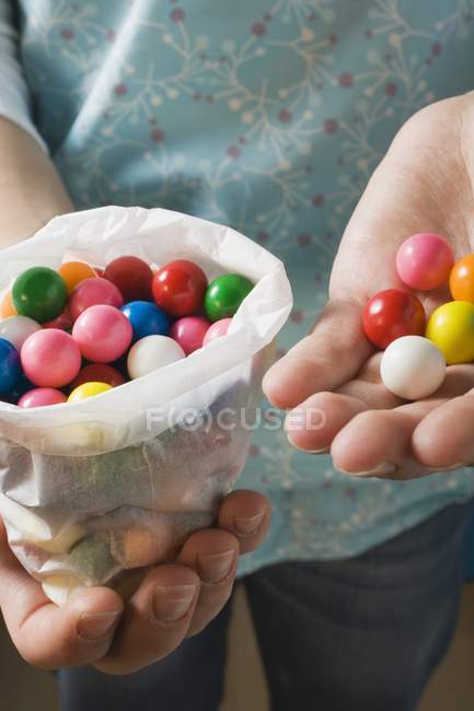 Cropped view of person holding colored bubble gum balls — Stock Photo