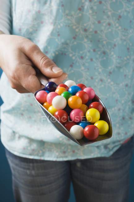 Cropped view of person holding scoop of colored bubble gum balls — Stock Photo