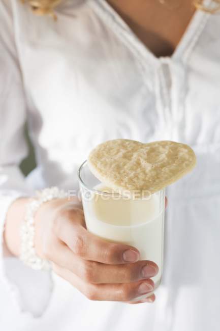 Vaso de leche con una galleta - foto de stock