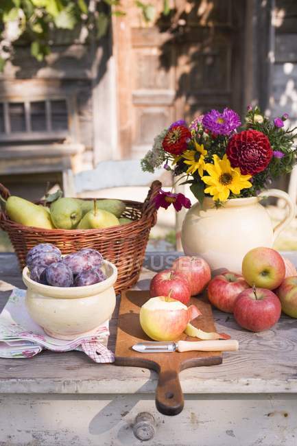 Vista diurna de la fruta rústica naturaleza muerta en la mesa de jardín cerca de la casa - foto de stock