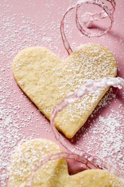 Primo piano dei cuori di pasticceria con zucchero a velo e nastro rosa — Foto stock