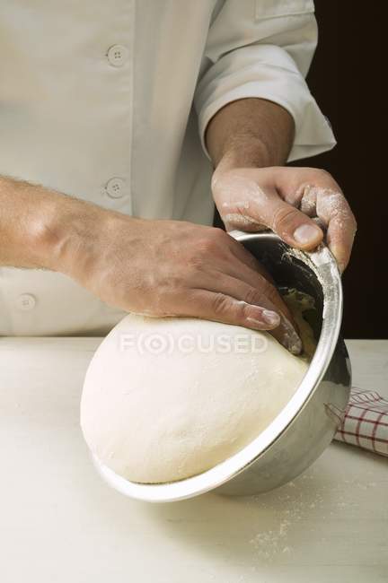 Шеф берет тесто для пиццы из миски — стоковое фото