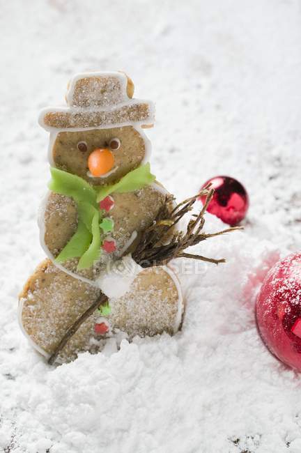 Closeup view of spiced pastry snowman in flour with Christmas baubles — Stock Photo
