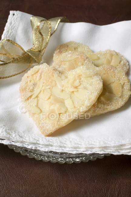 Vista de primer plano de los corazones de pastelería con almendras en copos y azúcar - foto de stock