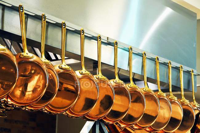 Vista close-up de panelas de cobre penduradas em uma fileira — Fotografia de Stock