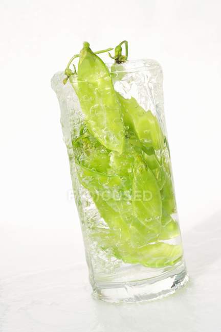 Ervilhas em vagens em vidro de água — Fotografia de Stock
