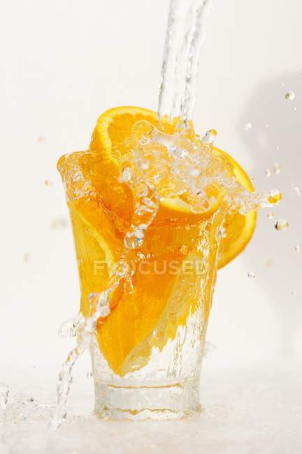 Salpicaduras de agua en naranjas en vidrio - foto de stock