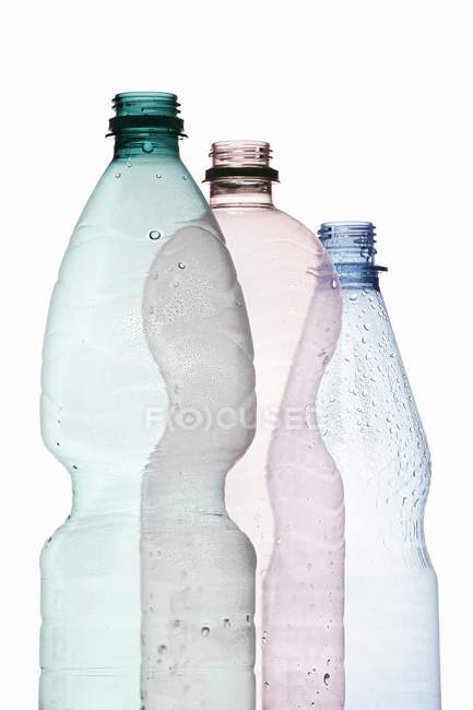 Vista de cerca de tres botellas de plástico abiertas sobre fondo blanco - foto de stock