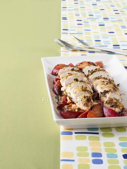 Chicken breast with herbs on plums — Stock Photo