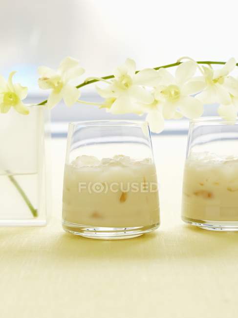 Vista de cerca del whisky helado de vainilla con Drambuie, extracto de vainilla, leche y orquídeas - foto de stock