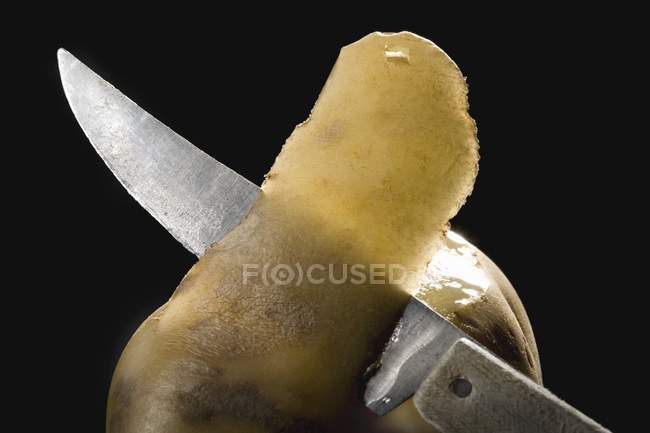 Peeling fresh potato with knife — Stock Photo
