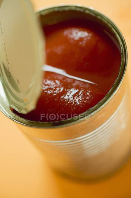 Tinned tomatoes over orange background — Stock Photo