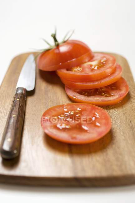 Rodajas de tomate y cuchillo - foto de stock