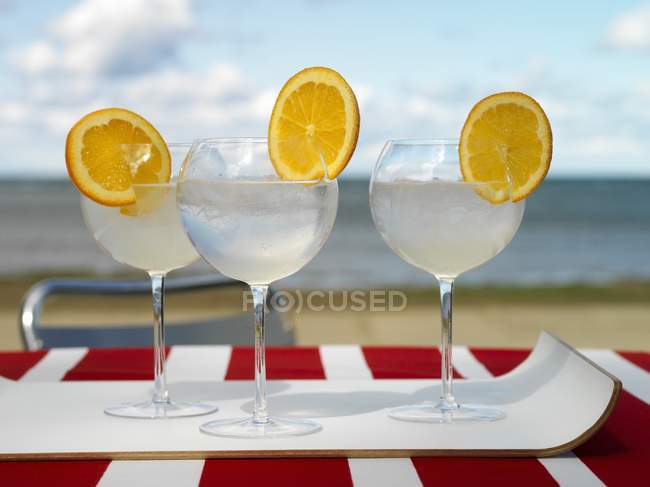 Крупный план апельсиновых тонизирующих коктейлей на пляже — стоковое фото