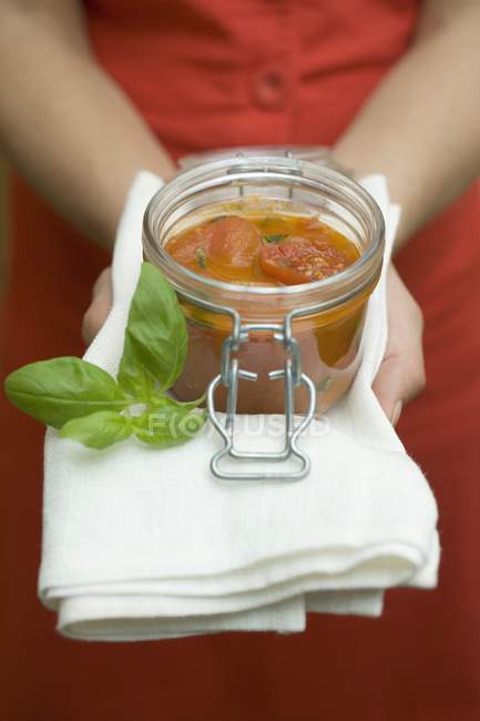 Hands holding preserving jar of tomato sauce — Stock Photo