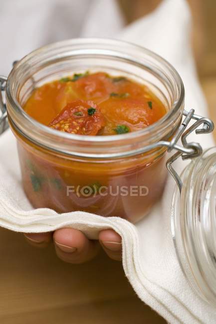 Hand holding preserving jar of tomato sauce with towel — Stock Photo