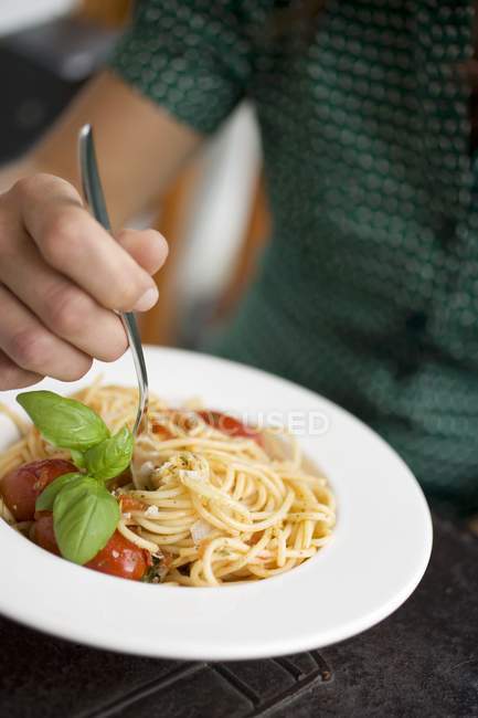 Mulher comendo espaguete com tomate — Fotografia de Stock