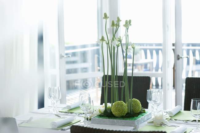Table de salle à manger avec arrangement floral, balcon lumineux derrière — Photo de stock