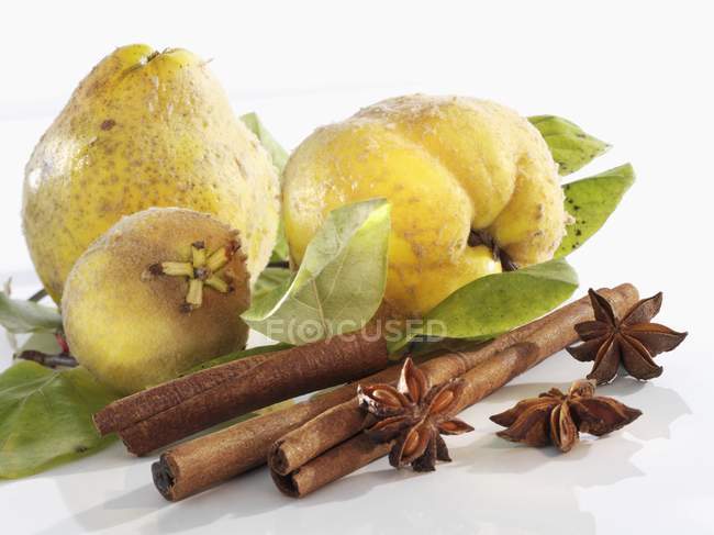 Quinces with leaves and cinnamon sticks — Stock Photo