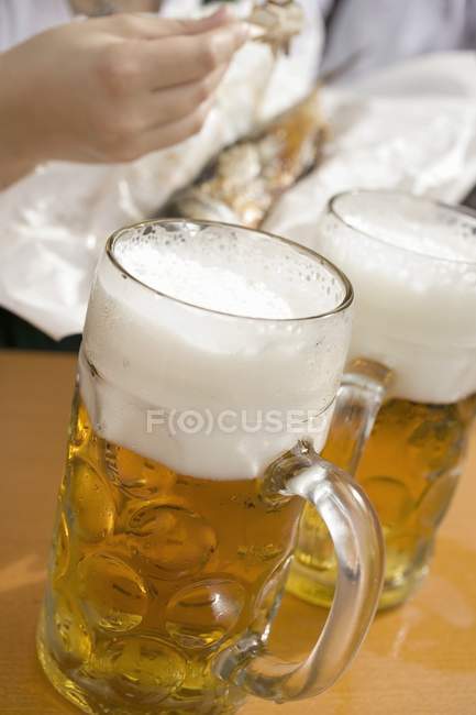 Tazas de cerveza en la mesa - foto de stock