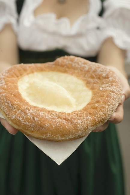 Cropped view of woman holding Auszogene Bavarian fried pastry on napkin — Stock Photo