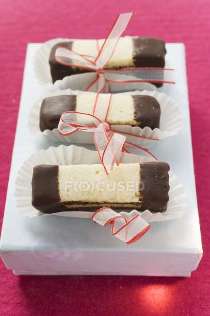 Vista de primer plano de chocolate en capas y barras de dedos lisos atados con cintas en la caja - foto de stock
