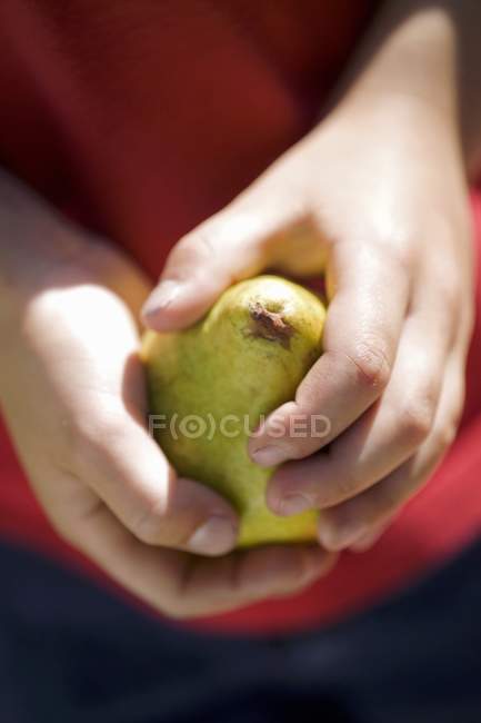 Enfant tenant une poire fraîche — Photo de stock