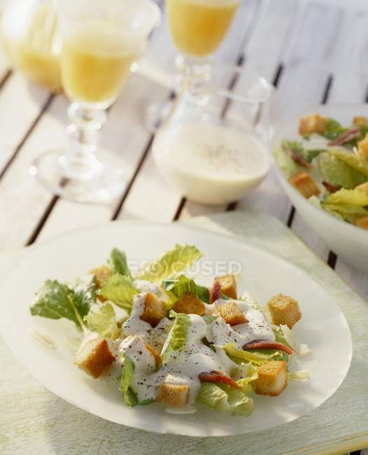 Vue rapprochée de la salade César sur assiette blanche avec sauce et jus — Photo de stock