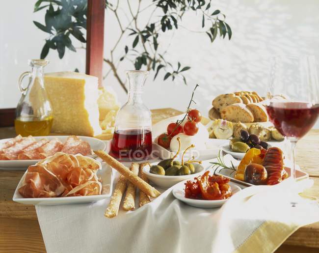 Uma mesa colocada com antipasti e vinho tinto — Fotografia de Stock