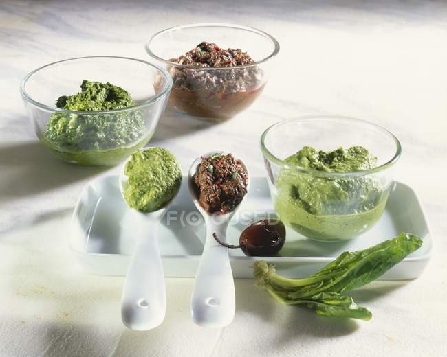 Spinat-Pesto mit Olivenpaste in Glasschalen über dem Tisch — Stockfoto