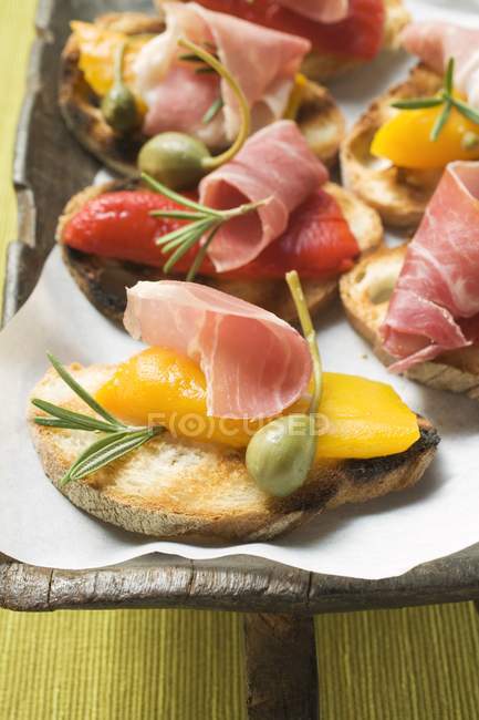 Crostini with raw ham and peppers — Stock Photo