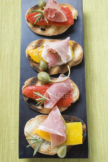 Crostini with raw ham and giant capers — Stock Photo