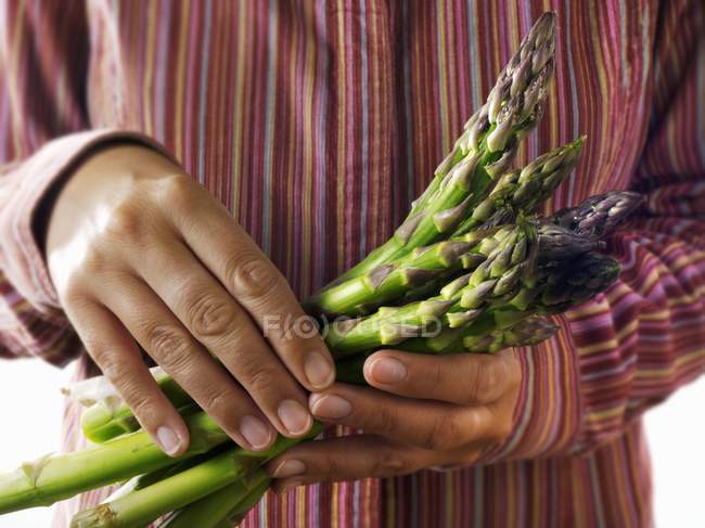 Person holding fresh green asparagus — Stock Photo
