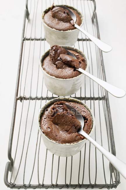 Vista close-up de três souffles de chocolate em tigelas cheias de molho de chocolate — Fotografia de Stock
