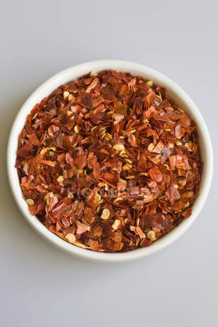 Dried chilli flakes in small white bowl — Stock Photo