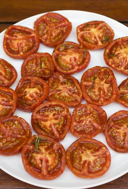 Mitades de tomate frito en plato blanco - foto de stock