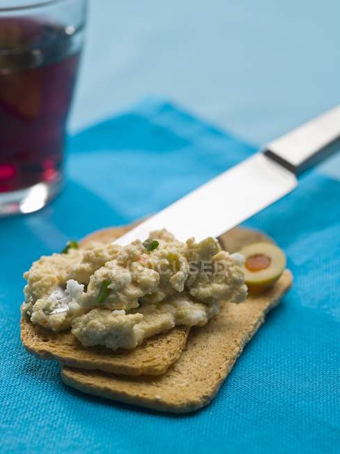 Scrambled egg with fish on Melba toast on blue tablecloth — Stock Photo