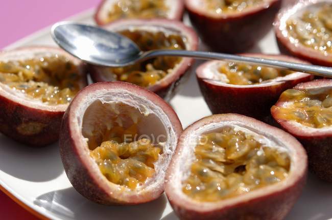 Halved passion fruits with spoon — Stock Photo