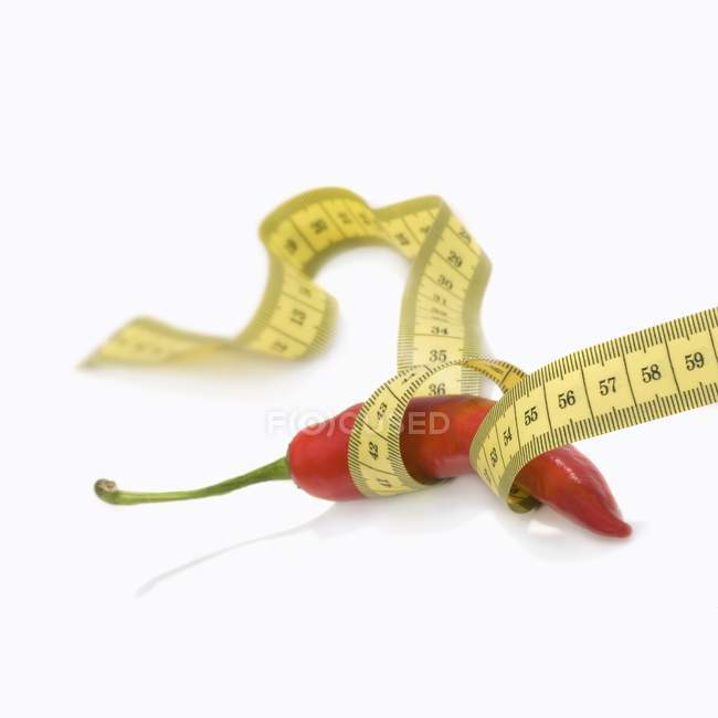 A chilli with a tape measure around it on white background — Stock Photo