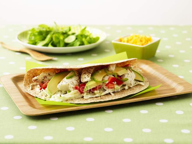 Burrito con halibut e avocado su vassoio sopra tovaglia verde — Foto stock