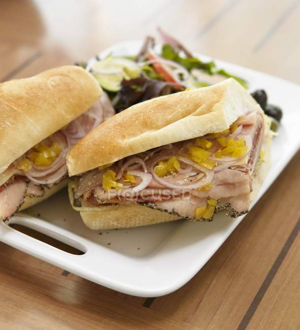 Sandwich italien, charcuterie avec oignon et piments forts sur Baguette sur plaque blanche — Photo de stock