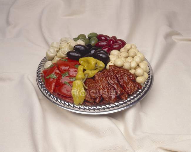 Platter with Sun Dried Tomatoes, Peperoncini, Olives and Mushrooms over cloth — Stock Photo