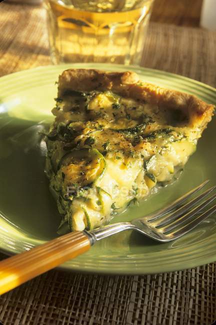 Slice of Zucchini Quiche on green plate with fork — Stock Photo