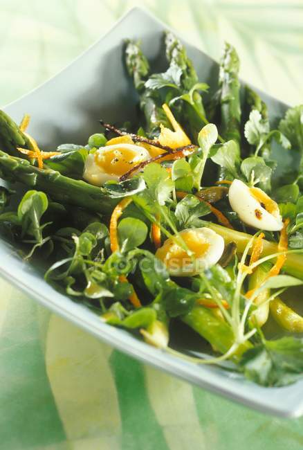 Spring salad with quail's egg on plate over green surface — Stock Photo