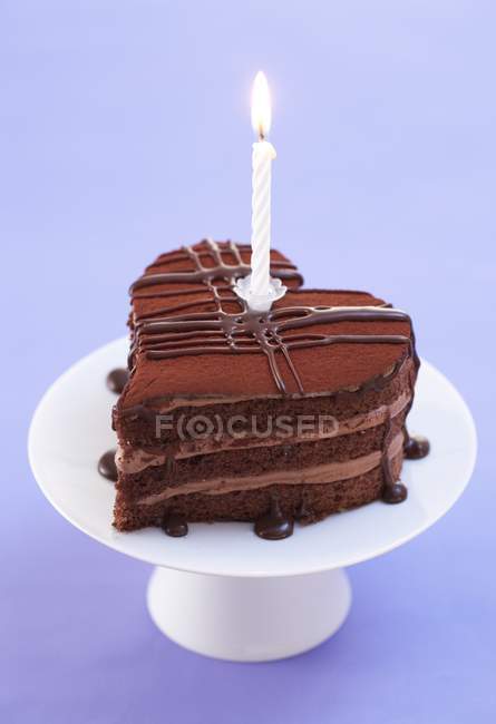 Closeup view of chocolate heart with one burning candle — Stock Photo