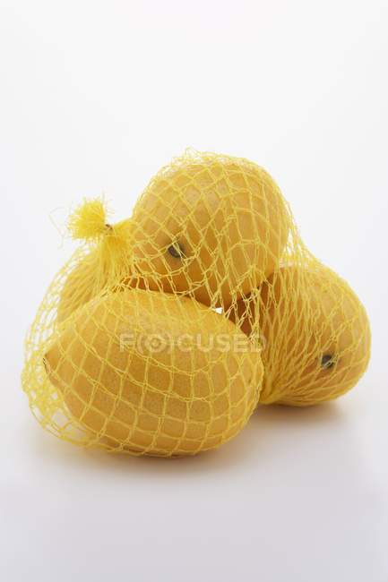 Четыре лимона в сетке — стоковое фото
