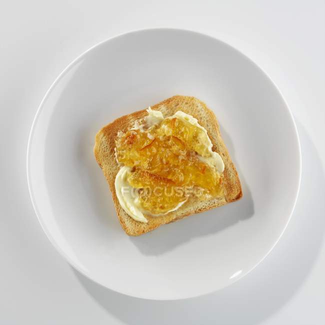 Vista de primer plano de tostadas con mantequilla y mermelada en el plato - foto de stock