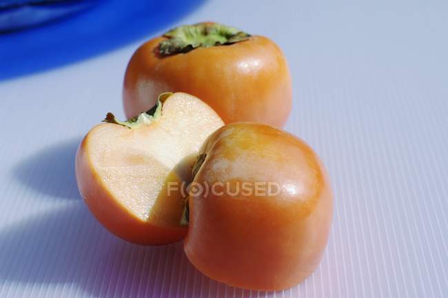 Whole and halved sharon fruits — Stock Photo