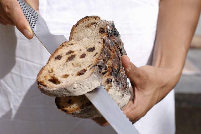 Человеческие руки режут кусок хлеба — стоковое фото