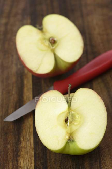 Pomme coupée en deux avec couteau — Photo de stock